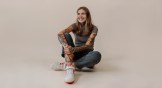 Brenna Blain sitting on the ground of a cream colored background