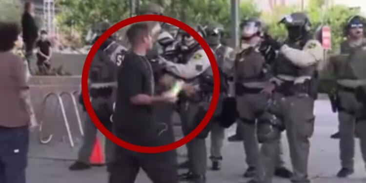 In a video posted to X on Wednesday, a rioter in Los Angeles threw an object at police, only to be tackled by a bystander when he turned to walk away.