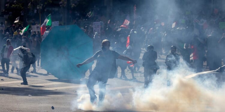 A protester kicks a tear gas canister at Sheriff deputies in Los Angeles, California, during the "No Kings" protest on Saturday.