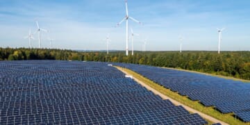 An aerial views shows a solar power station surrounded by a wind power plant.