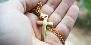 A gold cross in the palm of a hand.