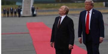 Russian President Vladimir Putin looks up as a U.S. Air Force B-2 Stealth Bomber and four jet fighters fly overhead. Putin arrived at Joint Base Elmendorf-Richardson in Alaska Friday to meet with President Donald Trump about the Ukraine War.