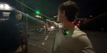 A masked antifa thug, left, was seemingly unaware of the sniper's green laser sight dot until the podcaster called his attention to it.