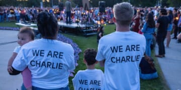 People wear t-shirts reading "We Are Charlie" as they pay their respects during a candlelight vigil for Charlie Kirk at a makeshift memorial at Memorial Park in Provo, Utah, on Sept. 12, 2025, after he was shot during a public event at Utah Valley University.