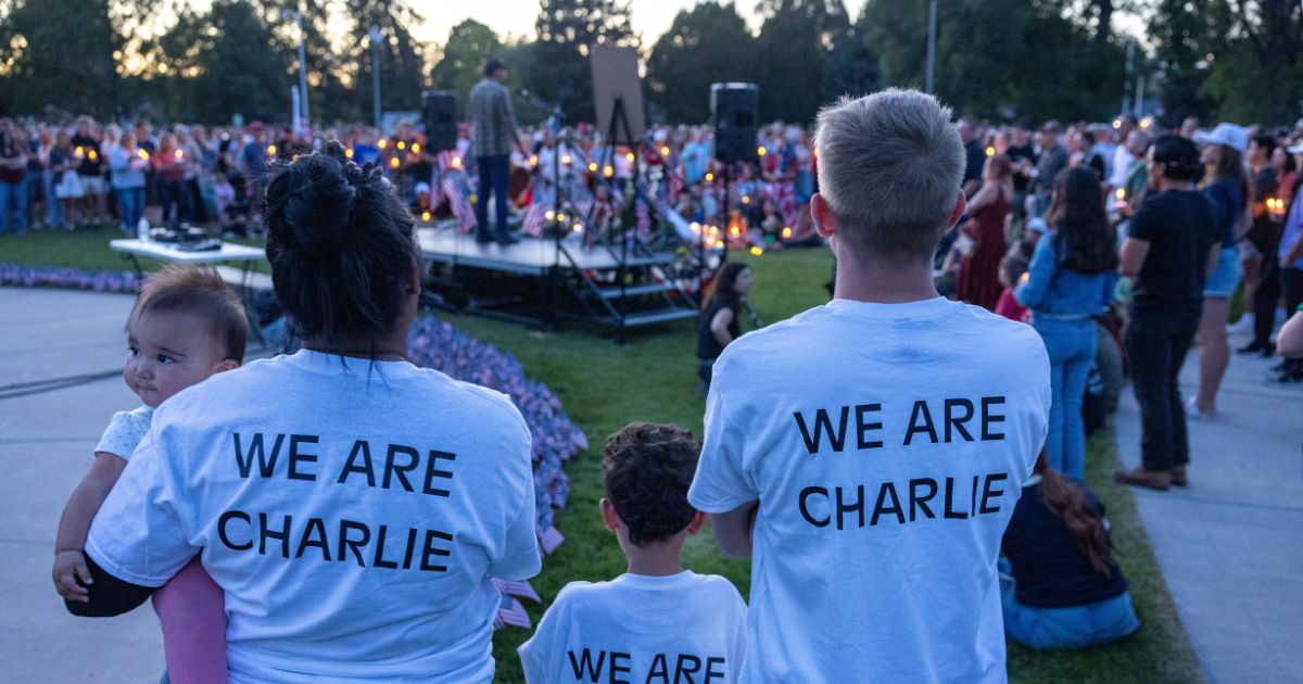People wear t-shirts reading "WW Are Charlie" as they pay their respects during a candlelight vigil for conservative activist Charlie Kirk at a makeshift memorial at Memorial Park in Provo, Utah, on Sept. 12, 2025, after he was shot during a public event at Utah Valley University.