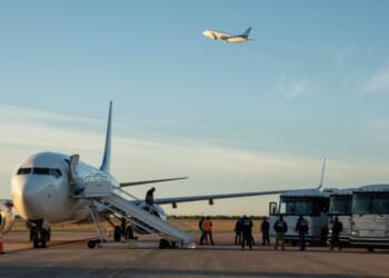 Buses transporting migrants to board the first deportation flight of illegal alien Venezuelans are seen as another deportation plane headed to Central America is seen flying above them in Harlingen, Texas, on Oct. 18, 2023.