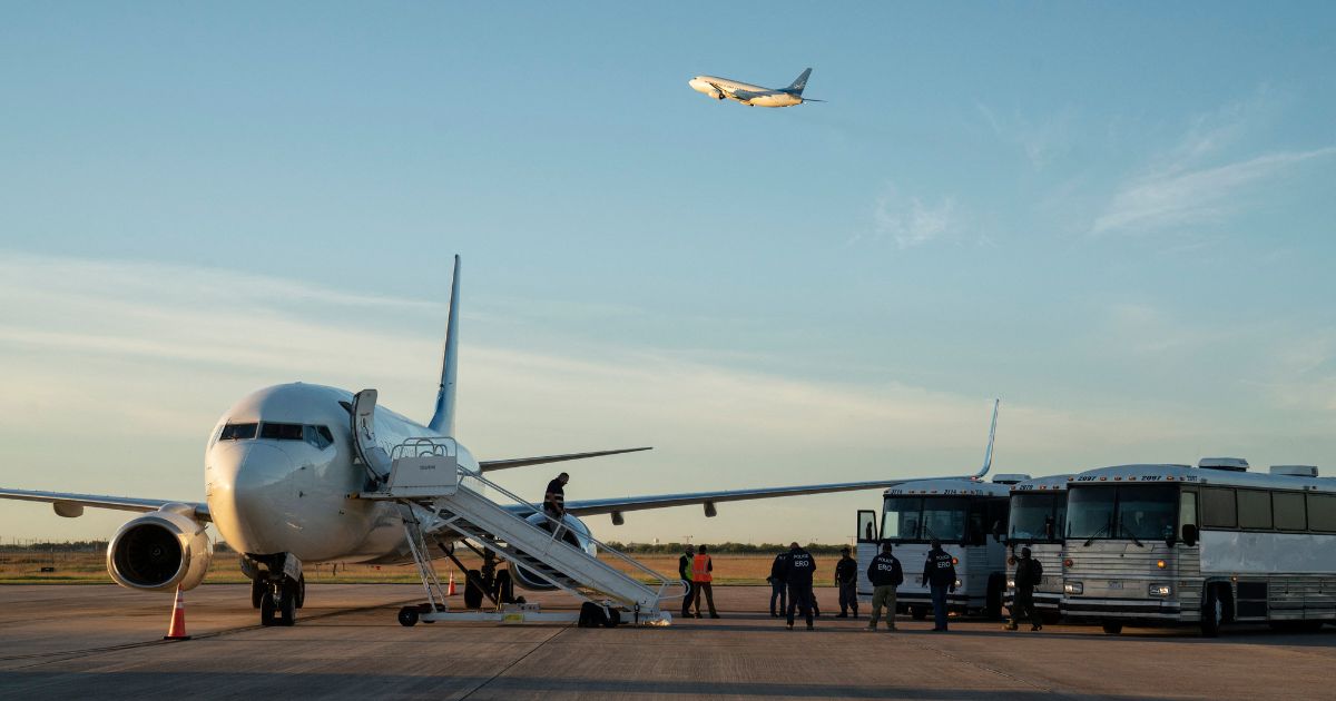 Buses transporting migrants to board the first deportation flight of illegal alien Venezuelans are seen as another deportation plane headed to Central America is seen flying above them in Harlingen, Texas, on Oct. 18, 2023.