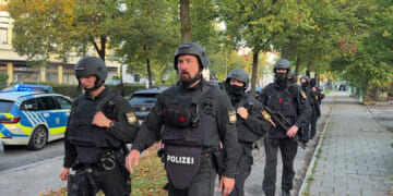 Police officers walk along a footpath after a fire in a detached house in Munich, Germany, on Wednesday.