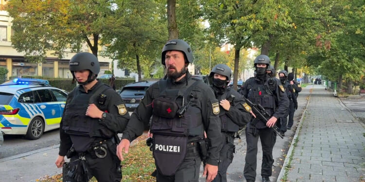 Police officers walk along a footpath after a fire in a detached house in Munich, Germany, on Wednesday.