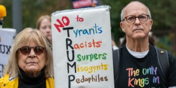 A crowd of mainly American anti-Trump protestors holds signs outside the U.S. Embassy in London during a "No Kings" protest against President Donald Trump on Oct. 18, 2025, in London, England.