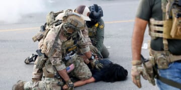 A person is detained by law enforcement officers in Chicago's Brighton Park neighborhood in Chicago on Oct. 4, 2025.
