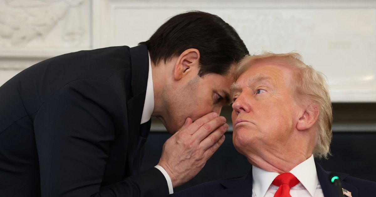 Secretary of State Marco Rubio interrupts a roundtable discussion to whisper to President Donald Trump at the White House Thursday.
