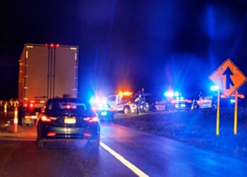 A stock photo shows a highway scene at night with emergency vehicles responding to an accident.