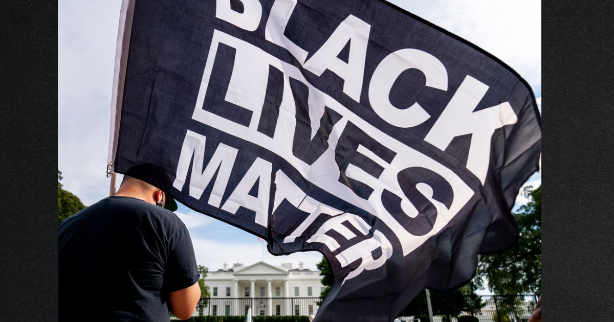 A man carries a Black Lives Matter flag in Lafayette Square outside the White House in a file photo from Aug. 27, 2020.