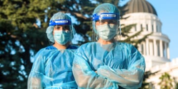 A stock photo shows masked health care workers in front of the state capitol building. Several California counties are mandating masks in health care settings from Nov.1 through March 31.