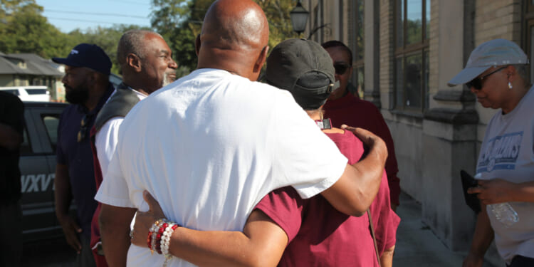 Friends and family of victims of a homecoming shooting embrace in downtown Leland, Mississippi, on Saturday.