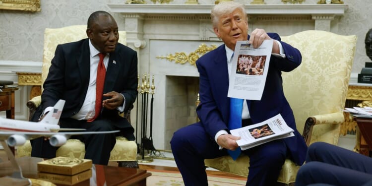President Donald Trump holds up a printed article from "American Thinker" while accusing South Africa President Cyril Ramaphosa of state-sanctioned violence against white farmers in South Africa during a press availability in the Oval Office at the White House on May 21, 2025, in Washington, D.C.