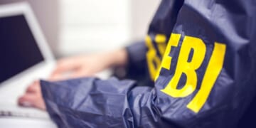 An FBI agent works at a computer in an office.