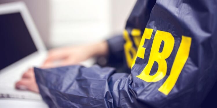 An FBI agent works at a computer in an office.