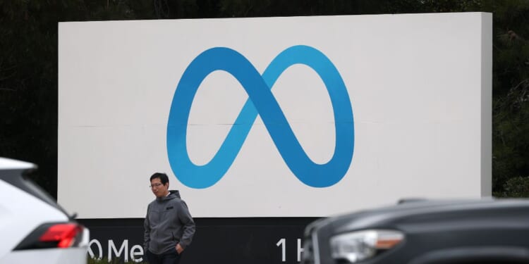 A visitor stands by a sign posted in front of Meta headquarters on Jan. 29, 2025, in Menlo Park, California.