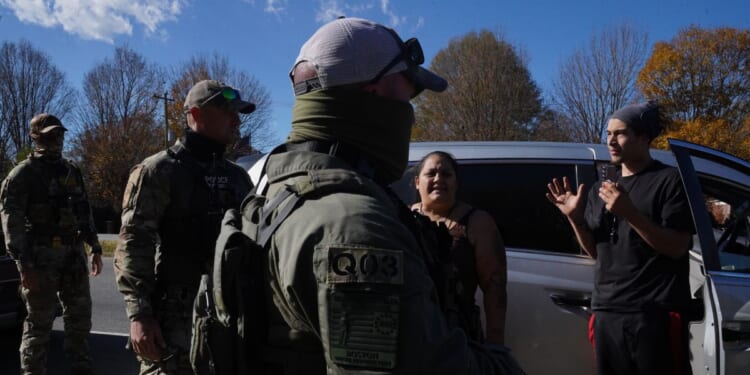 Department of Homeland Security Investigations officers question an individual after two people fled the scene while being stopped for selling flowers on the side of the road on Nov. 16, 2025, in Charlotte, North Carolina.