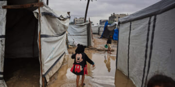 Palestinians walk through a flooded temporary tent camp Tuesday after heavy rainfall in Deir al-Balah, central Gaza Strip.