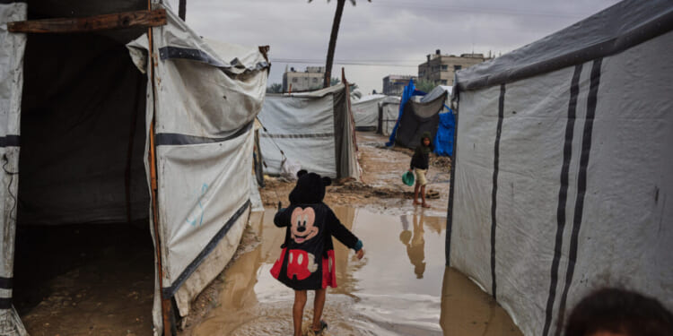 Palestinians walk through a flooded temporary tent camp Tuesday after heavy rainfall in Deir al-Balah, central Gaza Strip.