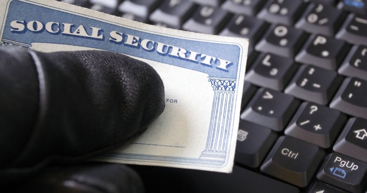 A man's hand holding a Social Security card.