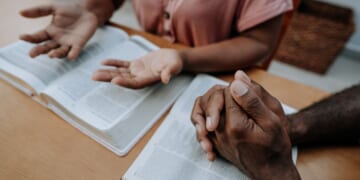 A couple prays together in a stock photograph.