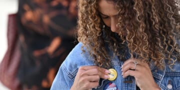 A young woman attaches a pin to her jacket after voting at a mobile outdoor vote center at SoFi Stadium in Los Angeles, California, on Election Day, Nov. 5, 2024.
