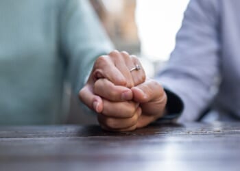A couple holds hands at a cafe table.
