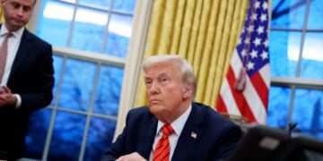 President Donald Trump, accompanied by White House Staff Secretary Will Scharf, appears at the Resolute Desk as he signs a series of executive orders including 25 percent tariffs on steel and aluminum, a pardon for former Illinois Gov.