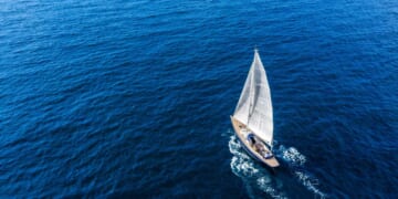 An aerial view of a sail boat floating in the Mediterranean sea.