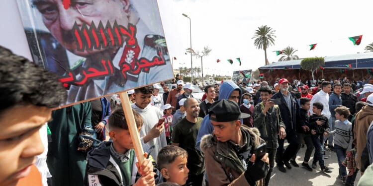 A youth hols up a sign at a protest in the coastal Libyan city of Tajura on Feb. 25, 2022.