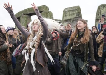 People cheer as the sun rises on winter solstice at Stonehenge