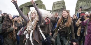 People cheer as the sun rises on winter solstice at Stonehenge