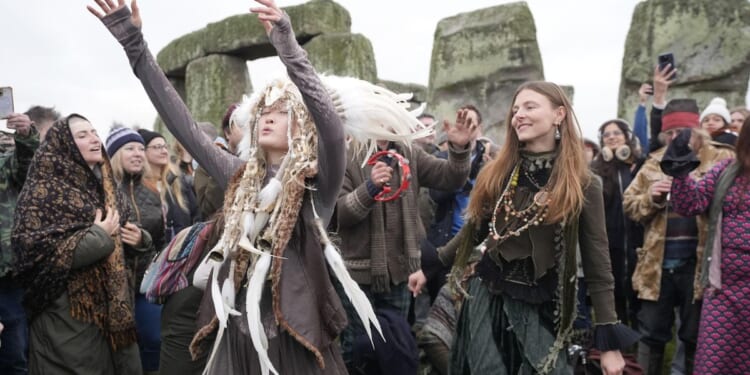 People cheer as the sun rises on winter solstice at Stonehenge