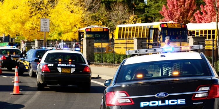 Police cars are parked near the entrance of a High School.