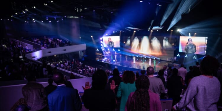 Believers pray during a worship service at the "Royal Cite" evangelical mega-church, which belongs to the "Impact Centre Chretien" international evangelic network, in Croissy-Beaubourg, east of Paris, on April 28, 2024.