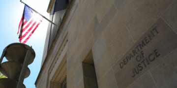 The US Department of Justice building and the American flag stand in the sun in Washington, DC.
