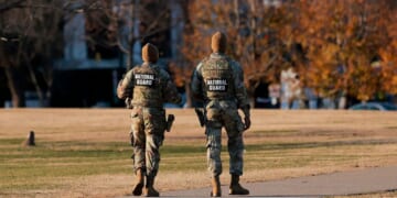 Two National Guard soldiers walk around the Washington Monument in Washington, DC on Dec. 1, 2025.