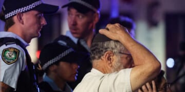 A member of the Jewish community reacts next to Australian law enforcement officers at the scene of the Bondi Beach shooting in Sydney on Dec. 14, 2025.