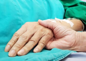 An oncologist doctor holds a patient's hand at a hospital.