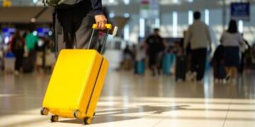 A traveler pulls his suitcase behind him at an airport.