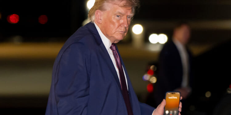 President Trump holds a cellphone during a call as he boards Air Force One at Rocky Mount-Wilson Regional Airport in Elm City, North Carolina, on Dec. 19, 2025.