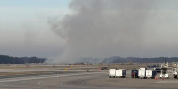 Smoke billows near a Dulles International Airport runway in Virginia on Dec. 13, 2025.