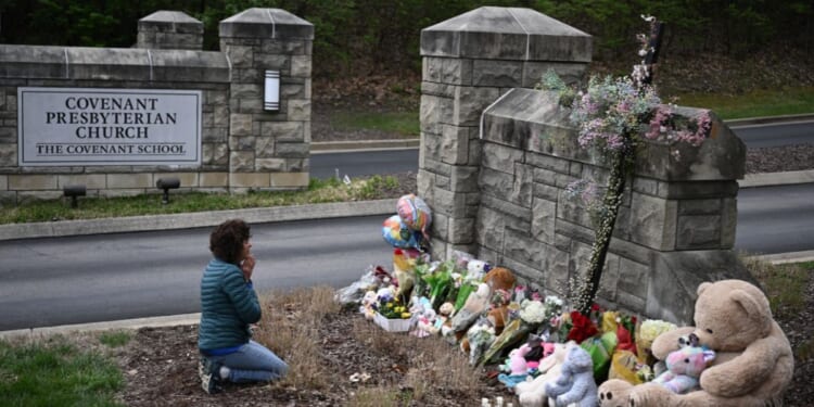 Robin Wolfenden prays at a makeshift memorial for victims outside the Covenant School building at the Covenant Presbyterian Church following a shooting in Nashville, Tennessee, on March 28, 2023.
