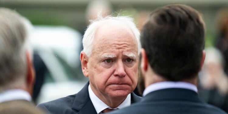 Minnesota Governor Tim Walz presents a Minnesota flag to a family after a funeral ceremony for DFL Rep. Melissa Hortman in Minneapolis, Minnesota, on June 28, 2025.