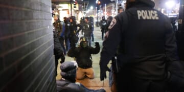 A protester on the ground raises his arms as law enforcement officers make arrests after Wednesday declaring an unlawful assembly during an anti-ICE demonstration in Minneapolis outside the Graduate by Hilton Minneapolis.