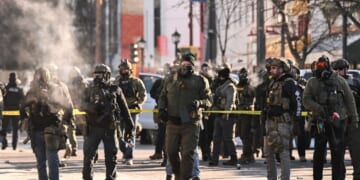 Federal agents stand near police tape as demonstrators gather near the site of where state and local authorities say a man was shot by federal agents earlier in the morning in Minneapolis, Minnesota, on Jan. 24, 2026.